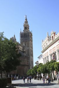 Tourist visiting building against clear blue sky
