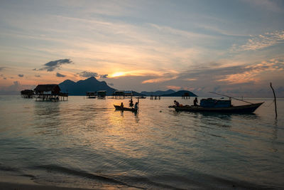 Silhouette boats in sea against sky during sunset