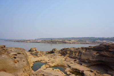 Rocks on beach against clear sky