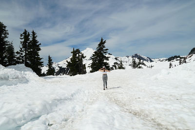 Rear view of person walking on snow covered mountain against sky