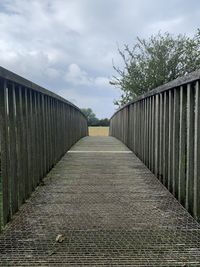 Empty footpath by railing against sky