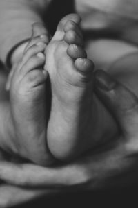 Cropped image of woman holding baby feet