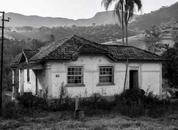 House on field by houses against sky