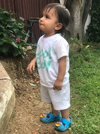 Cute boy looking away while standing on plants