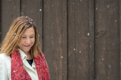 Smiling woman wearing warm clothing against wooden wall during winter