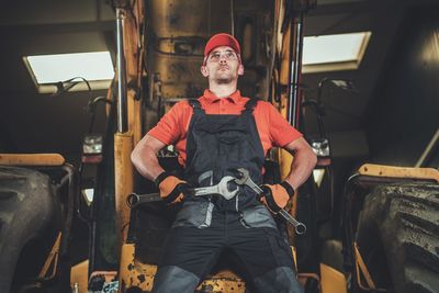 Man standing against earth mover in workshop