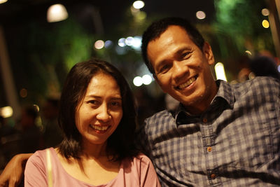 Portrait of smiling man and woman at night