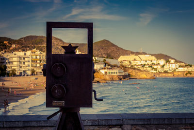 Close-up of coin-operated binoculars against city