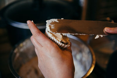 Cropped image of hand filling icing in cupcake