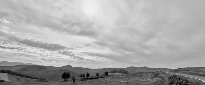 Panoramic view of road amidst field against sky