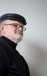 Close-up of senior man wearing flat cap and eyeglasses looking away at home