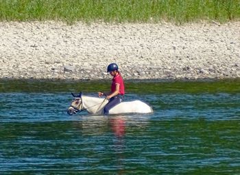 Full length of woman riding horse in water