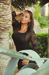 Portrait of smiling young woman against tree trunk