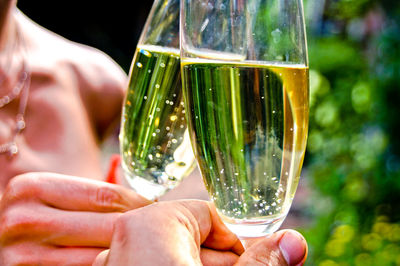 Cropped hands of friends toasting champagne flutes in yard