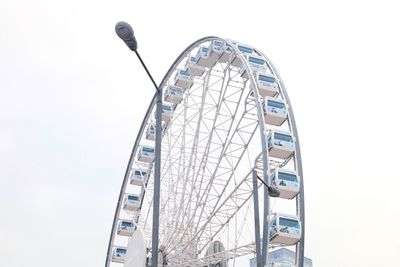 Low angle view of ferris wheel and street light against clear sky