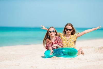 Portrait of sisters sitting on beach