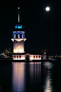 Illuminated building by river at night