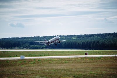 Airplane flying over runway against sky