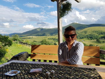 Woman sitting on table against landscape