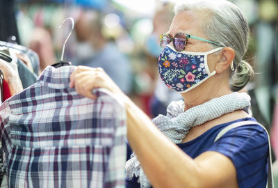 Close-up of senior woman wearing mask standing at store