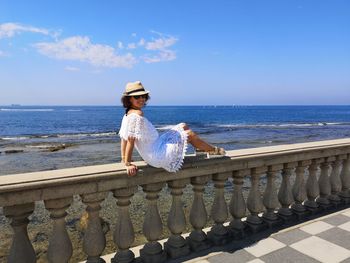 Woman on railing against sea against sky