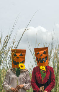 Women wearing mask standing on field against sky