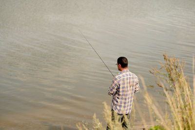 Rear view of man fishing in lake