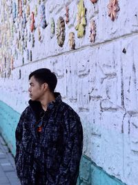 Young woman standing against wall