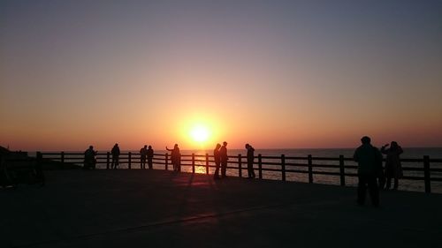 Silhouette people standing on promenade against sky during sunset