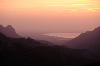 Scenic view of silhouette mountains against orange sky