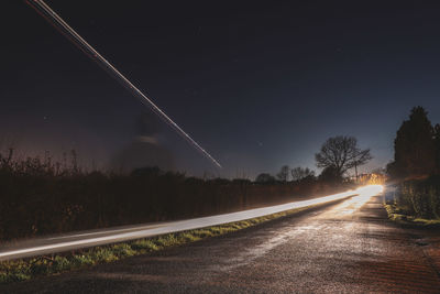 Light trails on road against sky at night