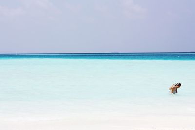 Woman in water at beach against sky