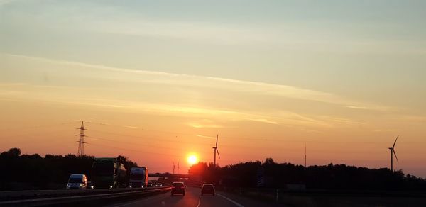 Cars on road against sky during sunset