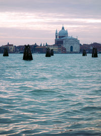 View of buildings in sea against cloudy sky