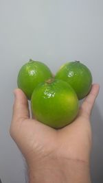 Cropped image of person holding apple against white background