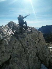 Man standing on rock against sky