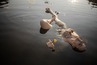 Mysterious and fashion portrait of young woman lying in water with face