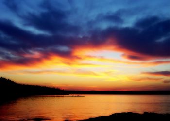 Scenic view of lake against cloudy sky at sunset