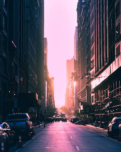 Traffic on city street amidst buildings against sky