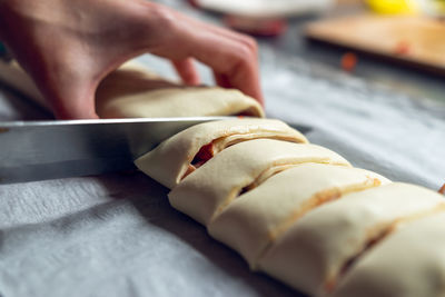 Female hands cut the rolled puff pastry into equal pieces. 