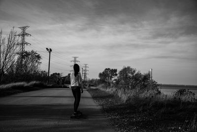 Rear view of woman walking on road against sky