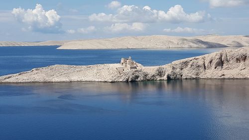 Scenic view of sea by mountain against sky