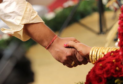 Cropped image of bride and bridegroom holding hands during wedding ceremony