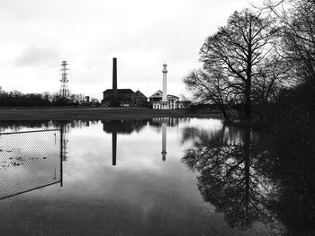 Reflection of factory on lake against sky