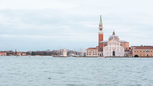 View of buildings at waterfront against cloudy sky