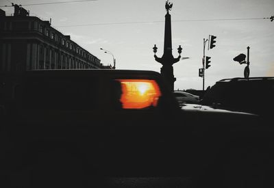 Silhouette of city street against sky during sunset