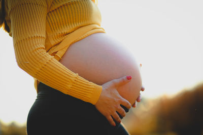Close-up of pregnant woman touching abdomen