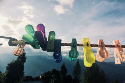 Low angle view of multi colored clothespins on rope against sky