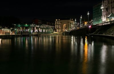 Illuminated bridge over river in city at night