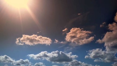 Low angle view of sunlight streaming through clouds